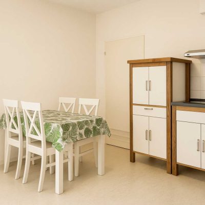 Esszimmer mit Esstisch, vier Stuehlen und angrenzender Kueche im Studentenwohnheim Hildebrandstrasse Dresden